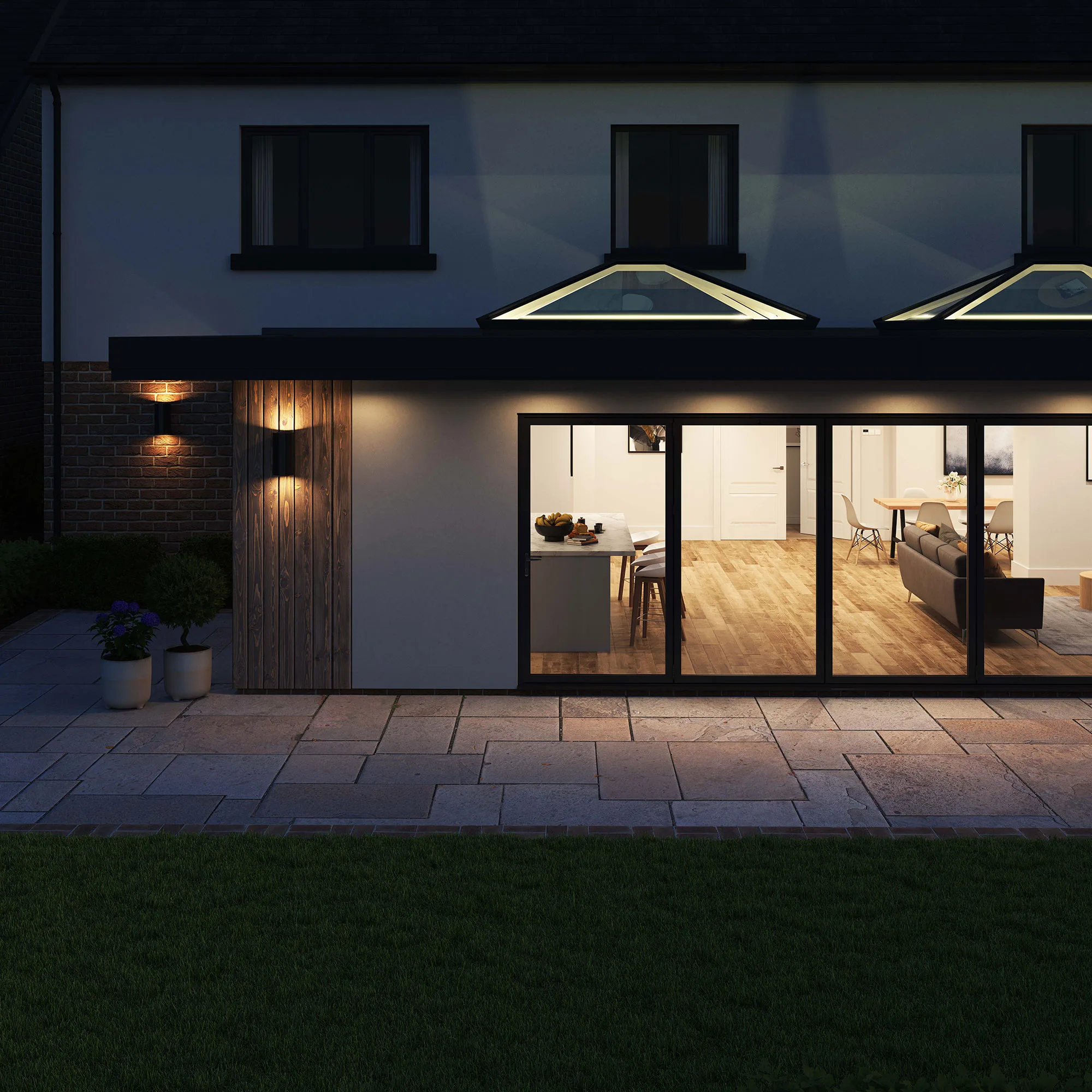 Exterior view at night showcasing two Korniche Roof Lanterns with internal lighting creating an uplighting effect on their architectural structure.