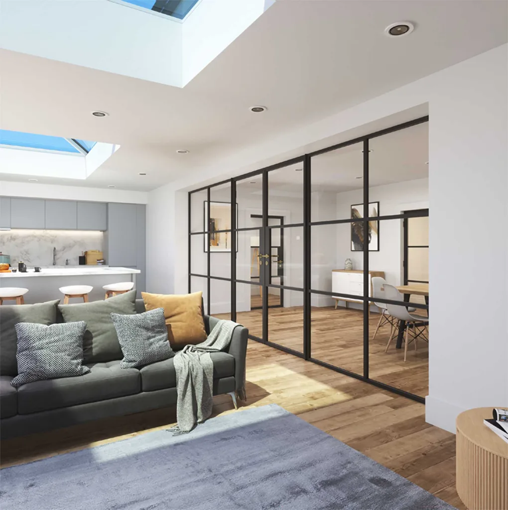 Korniche glass partition system creating a sleek and open-plan interior in a home in Stockton-on-Tees, England. The black framed glass doors and sidelights divide a dining area with a wooden table and chairs from a living room featuring a grey sofa and natural light.