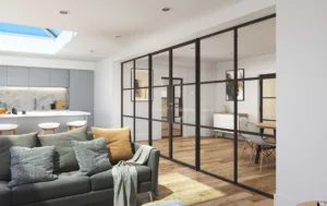 Korniche glass partition system creating a sleek and open-plan interior in a home in Stockton-on-Tees, England. The black framed glass doors and sidelights divide a dining area with a wooden table and chairs from a living room featuring a grey sofa and natural light.