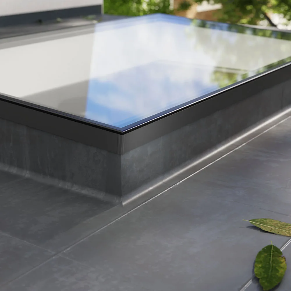 Close-up of a Korniche Flat Glass rooflight corner on a flat roof, highlighting the sleek black frame and replaceable glass unit.