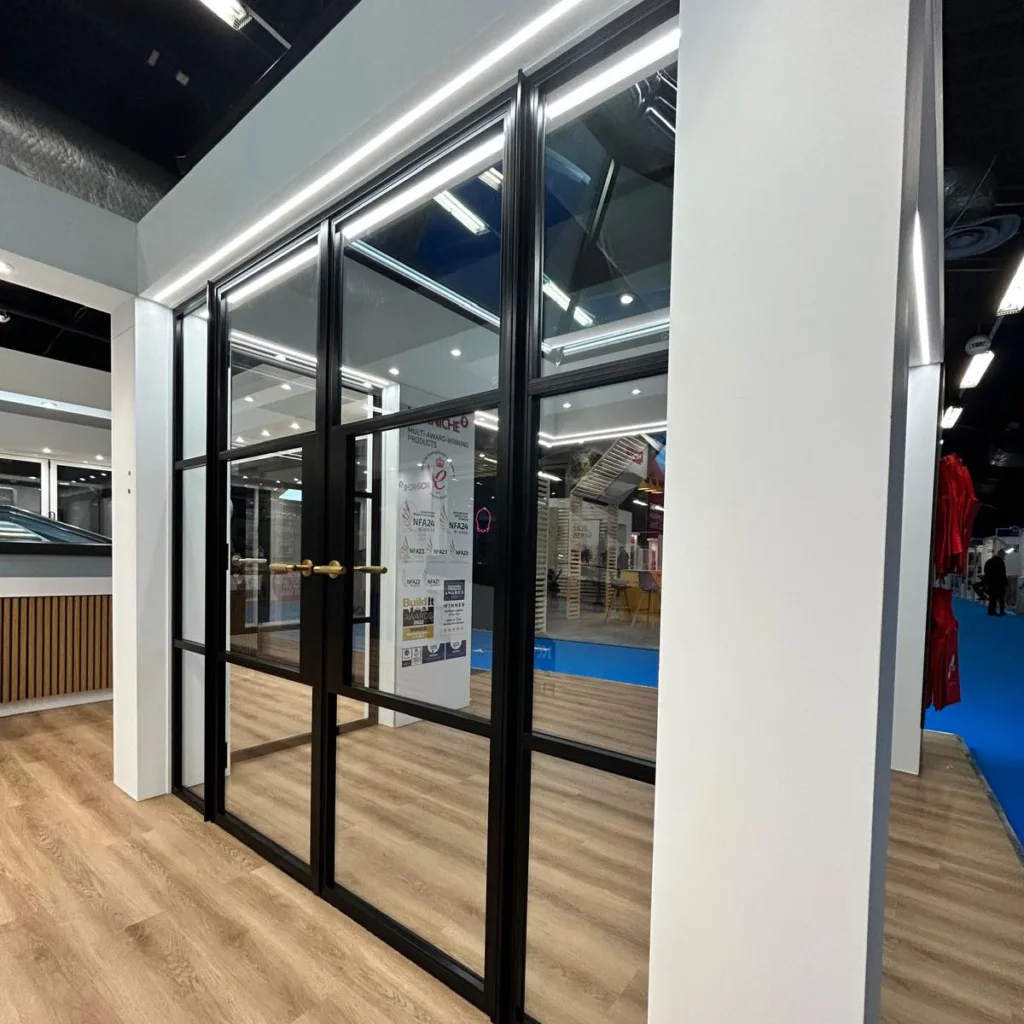 A stylish internal glass partition with slim black frames, dividing a room while maintaining an open, light-filled atmosphere.