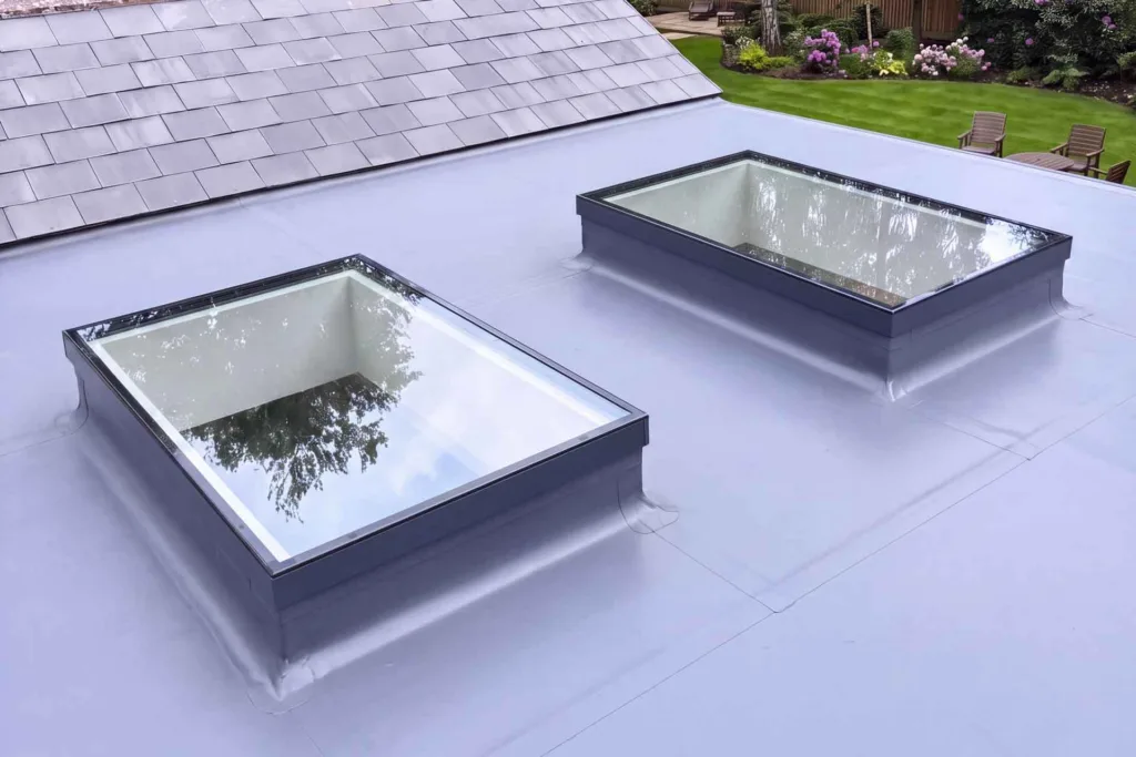 Two Korniche Flat Glass Rooflights with anthracite grey frames installed on a flat roof extension.