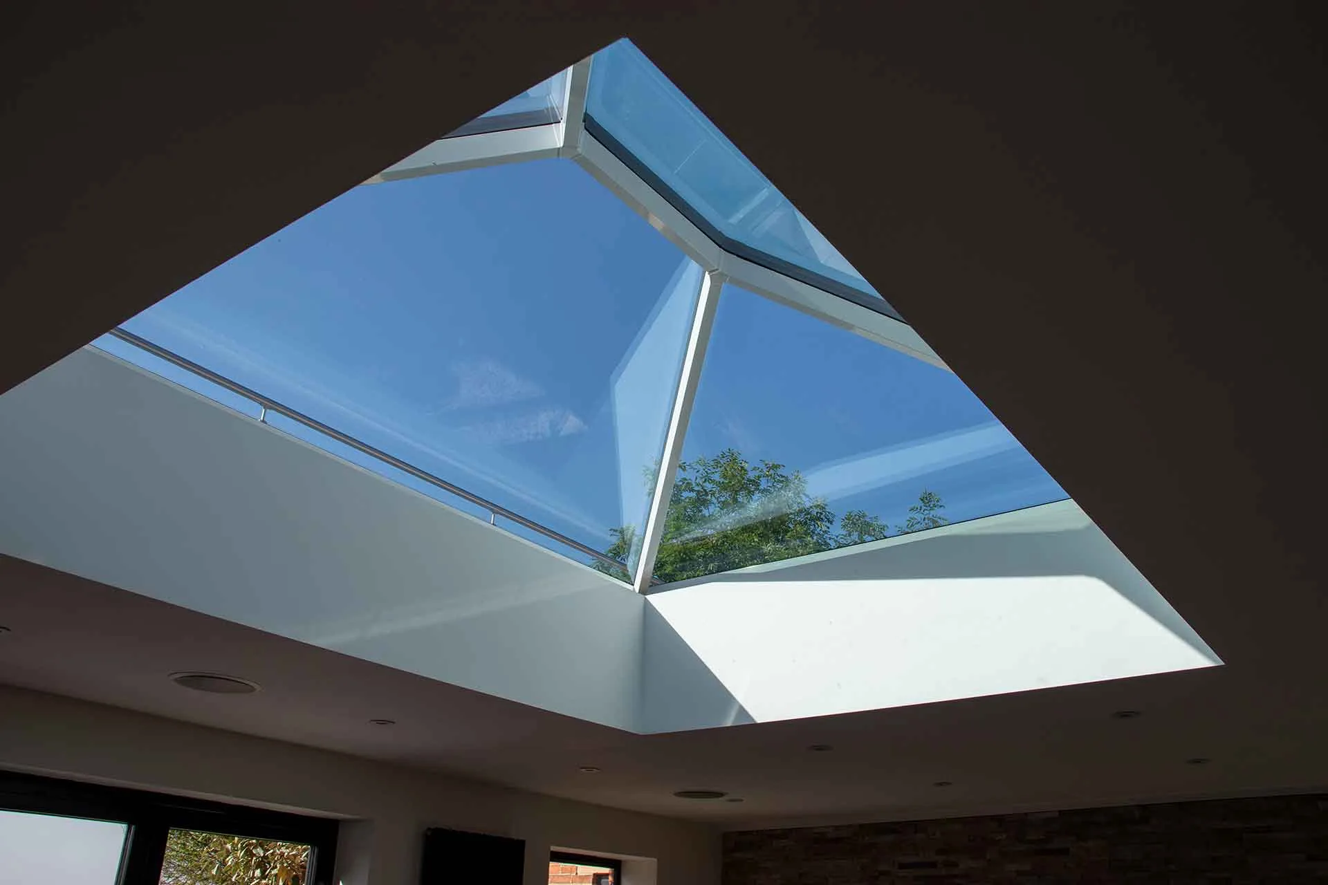 Interior view looking up through a white Korniche Roof Lantern towards a clear blue sky.