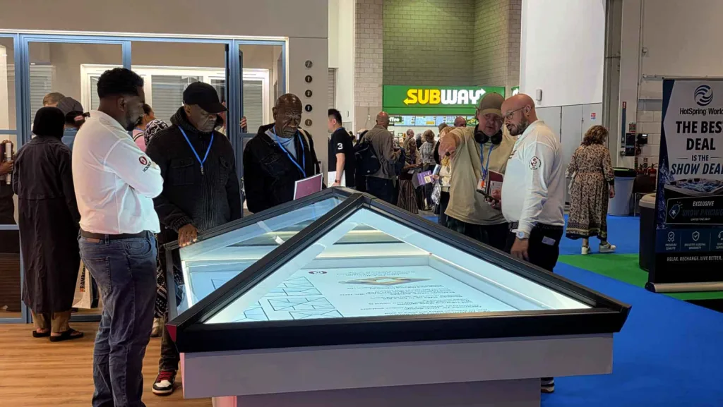 Korniche technical experts demonstrating an illuminated glass roof lantern display to interested visitors at the London Homebuilding & Renovating Show.