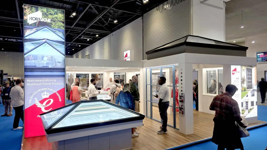 Wide shot of the busy Korniche Stand F101 showcasing aluminium home products, bi-fold doors, and roof lanterns at ExCeL London 2026.