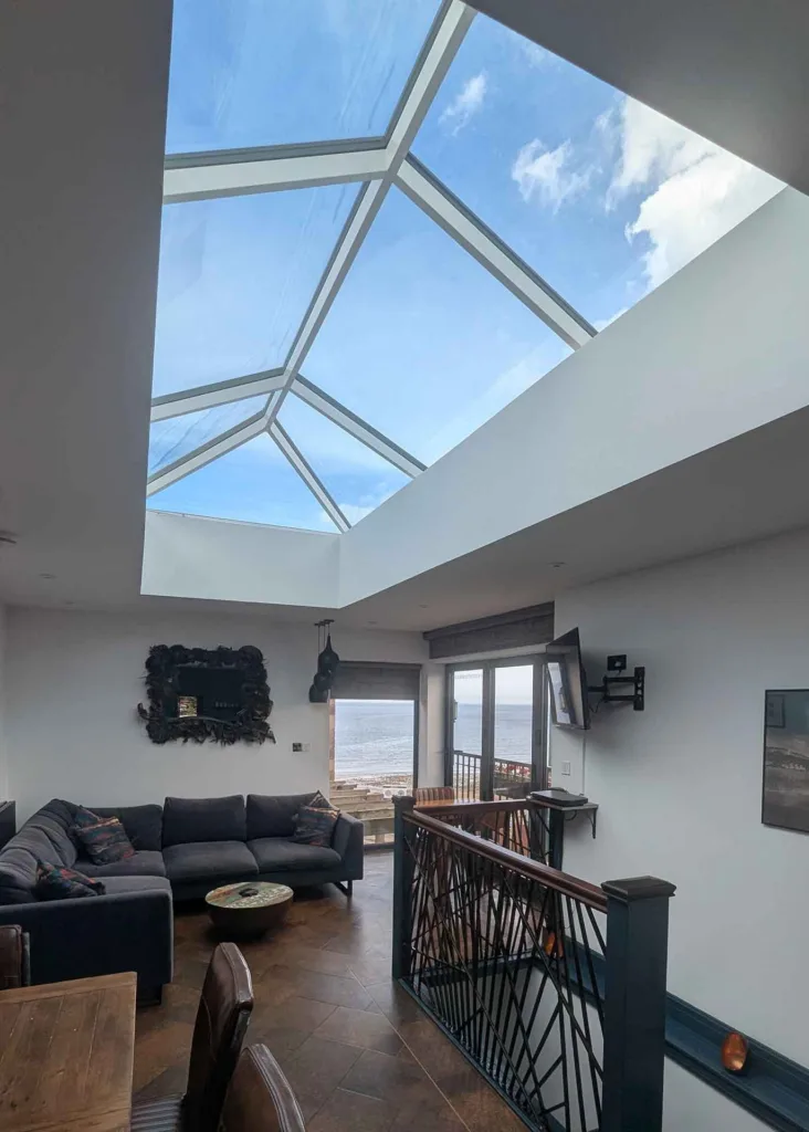 Spacious extension featuring a Korniche roof lantern and a comfortable sofa area overlooking the sea