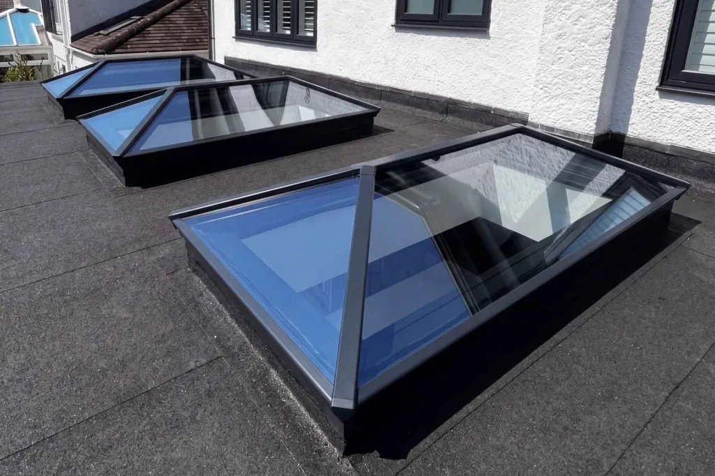 Three Korniche aluminium Roof Lanterns with dark grey frames installed on a flat roof extension, viewed from above.
